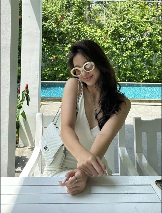 Huệ Anh nữ tính khi diện đầm hai dây màu kem trong một chuyến đi nghỉ. Con gái Kim Huệ ưa thích kiểu tóc dài ngang lưng, uốn xoăn nhẹ.